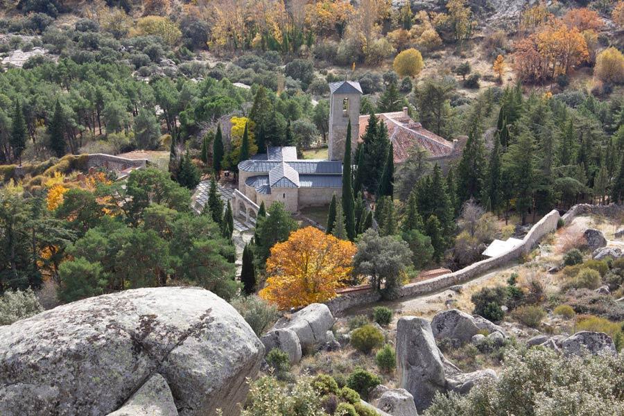 Vista a&eacute;rea de un sereno monasterio enclavado entre frondosos &aacute;rboles verdes y follaje oto&ntilde;al, rodeado de terreno rocoso.